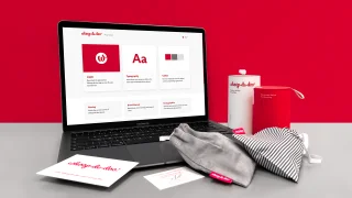 Notebook s online grafickým manuálem Whoop·de·doo vedle produktových obalů a vizitek značky